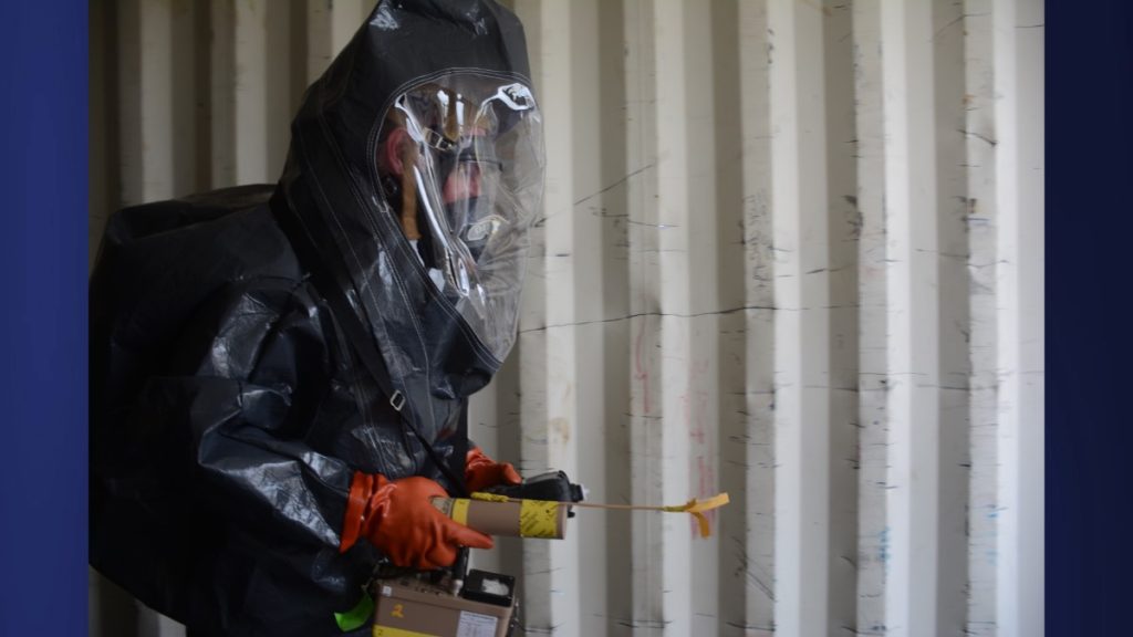A member of the Kaua'i Fire Department in full hazmat gear tests for radiation in a shipping container at Nāwiliwili Harbor on July 24, 2025. (Xiomara Yamileth/ Kaua'i Now)